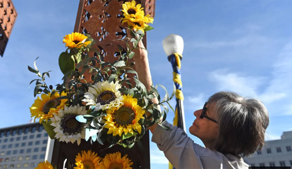 woman hanging flowers on post in solidarity with the Ukraine people
